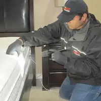 Bed bug inspection technician checking a mattress and bed frame for signs of infestation in Boston, MA