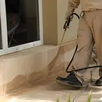 General pest control technician spraying exterior perimeter around a home in Boston, MA