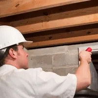 Termite inspection technician checking a basement wall and framing for termite activity in Boston, MA