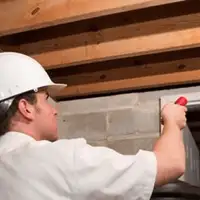 Termite inspection technician checking a basement wall and framing for termite activity in Boston, MA